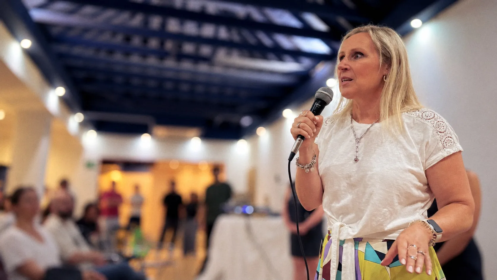 Kirsten speaking into a microphone at a live event