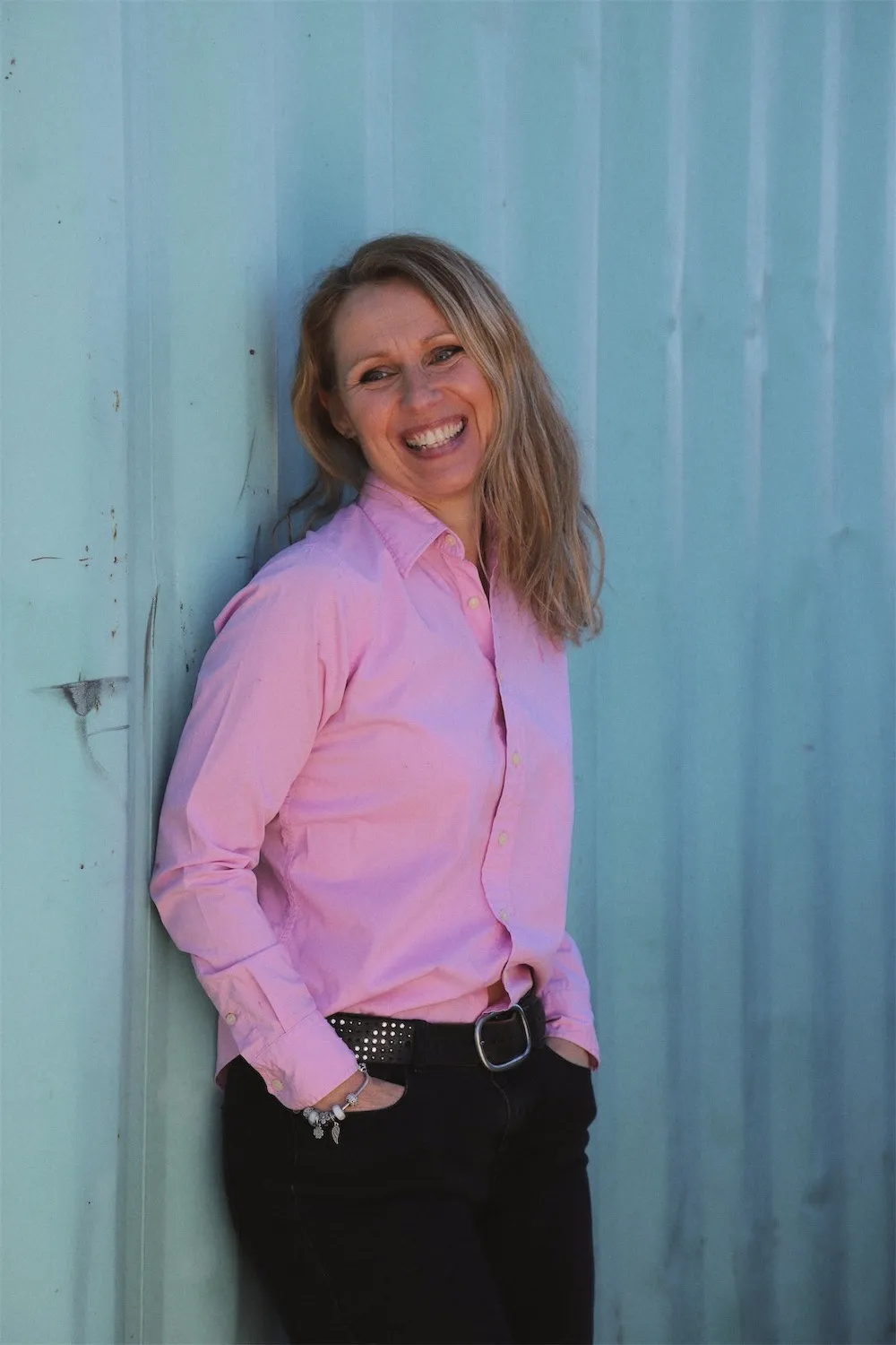 Kirsten laughing, leaning against a blue wall