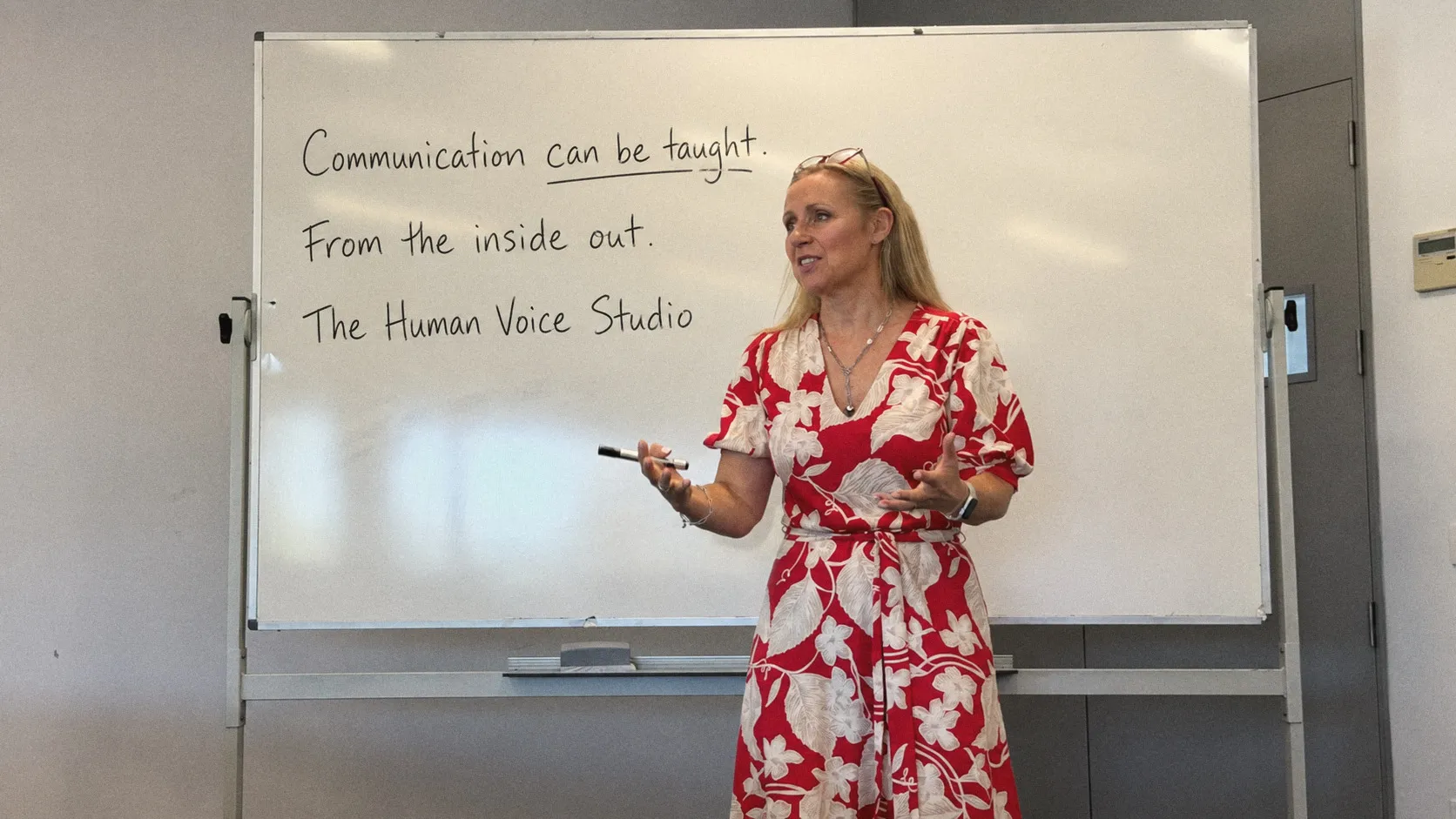 Kirsten at a whiteboard that reads: Communication can be taught. From the inside out. The Human Voice Studio