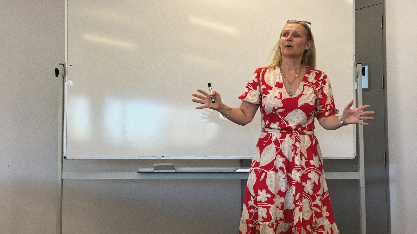 Kirsten speaking in front of a whiteboard, marker in hand
